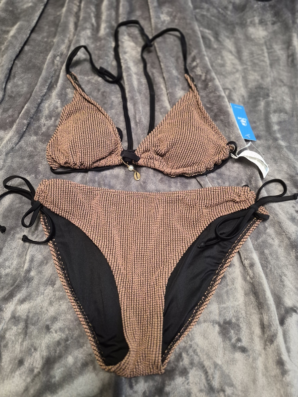 Cupshe Textured Copper Triangle Bikini Set with Black Trim and Seashell On Top.